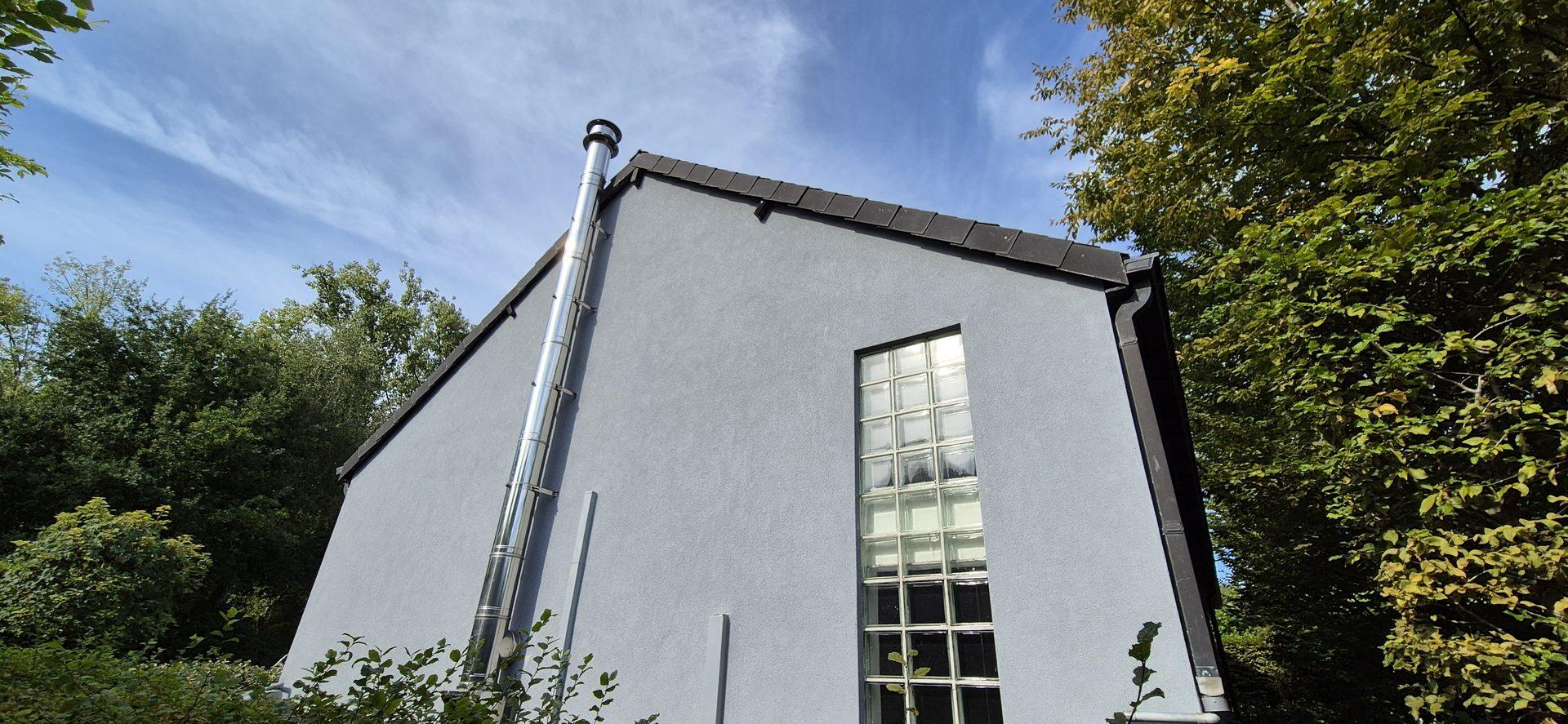 Gevelwerken in Bonheiden: puntgevel met lichtgrijze crepi en inox rookkanaal door Recotex