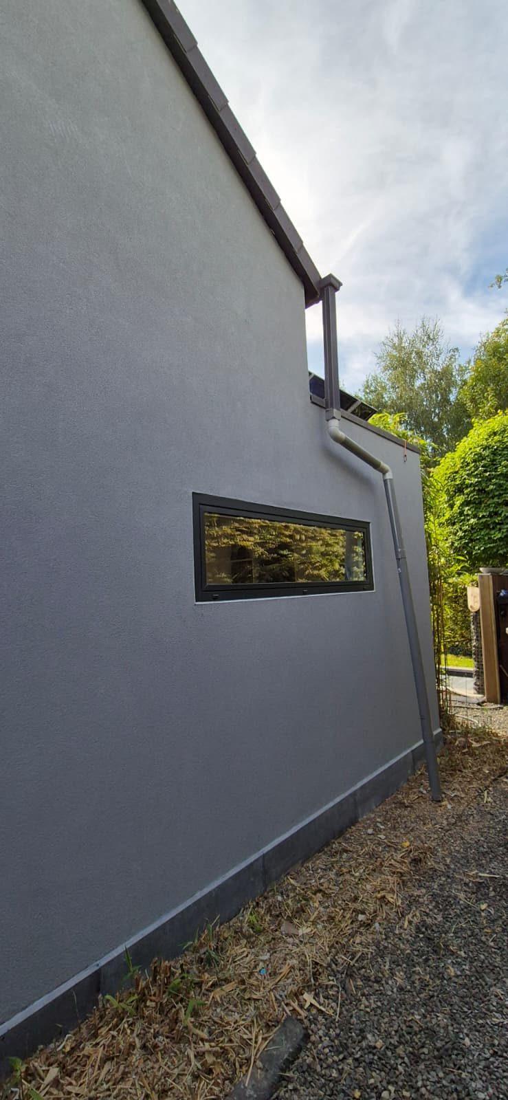 Zijgevel met bandraam en nieuwe regenafvoer na de gevelwerken in Bonheiden