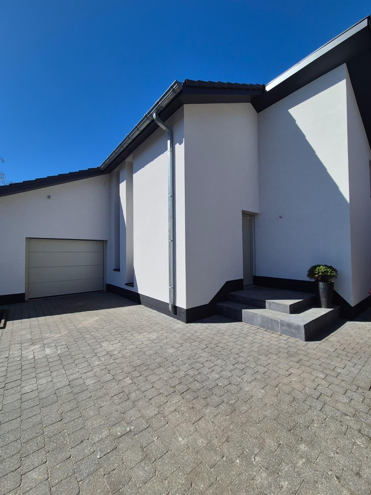 Inkomzone met garagepoort en witte crepi in Zoersel