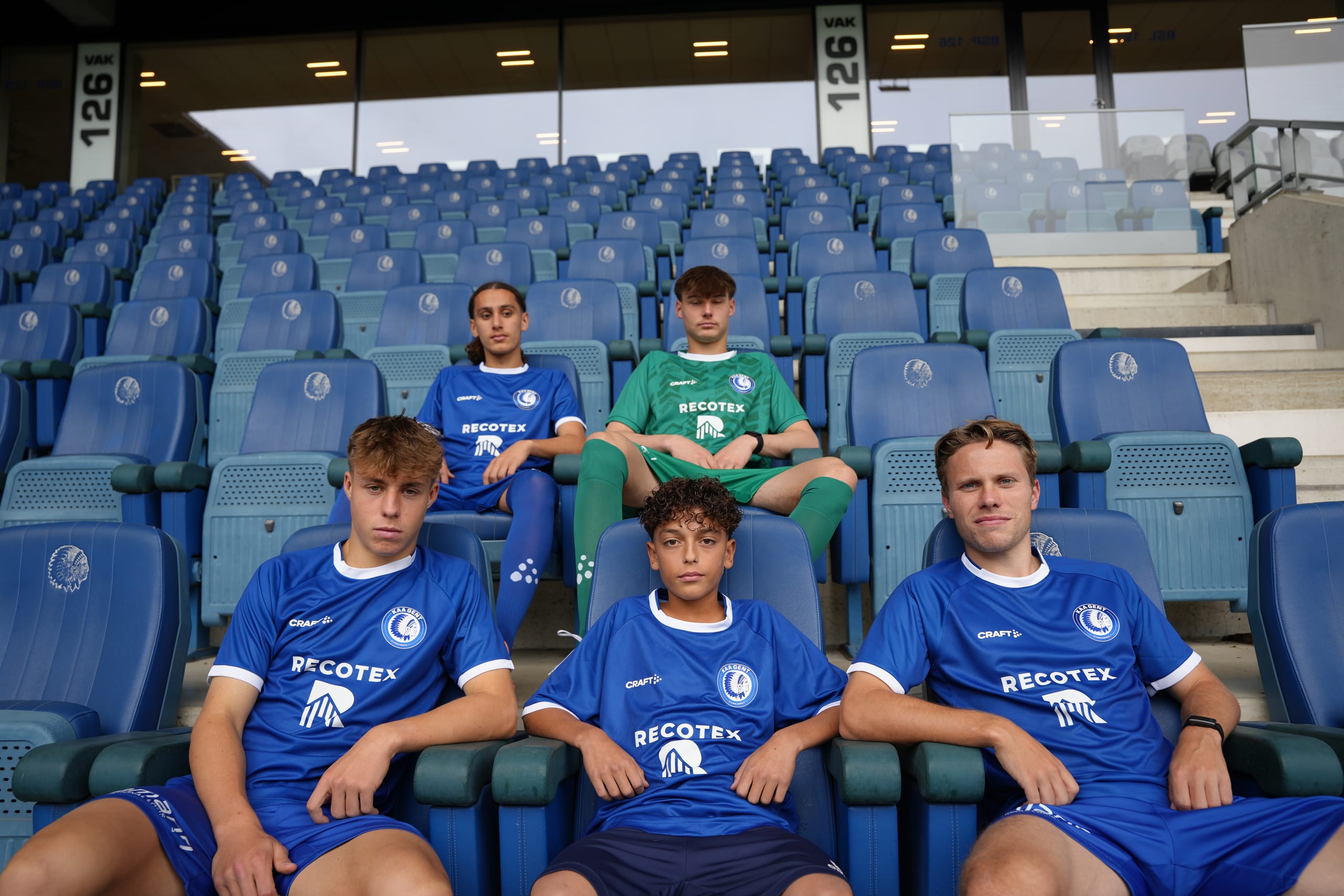 Jeugdspelers van KAA Gent in Recotex-shirts op de tribune van het stadion
