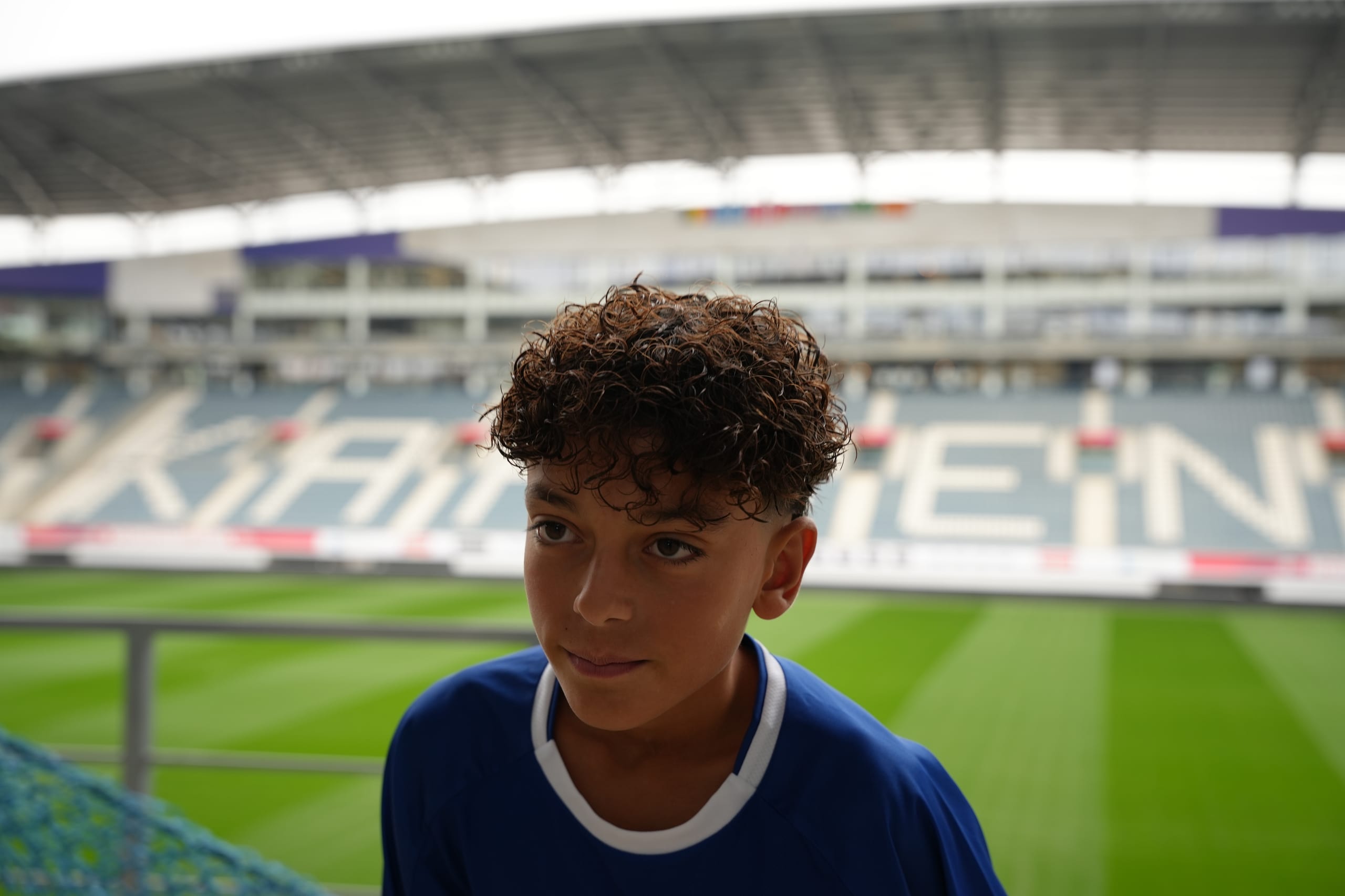 Een jonge speler van KAA Gent kijkt uit over het veld van het stadion